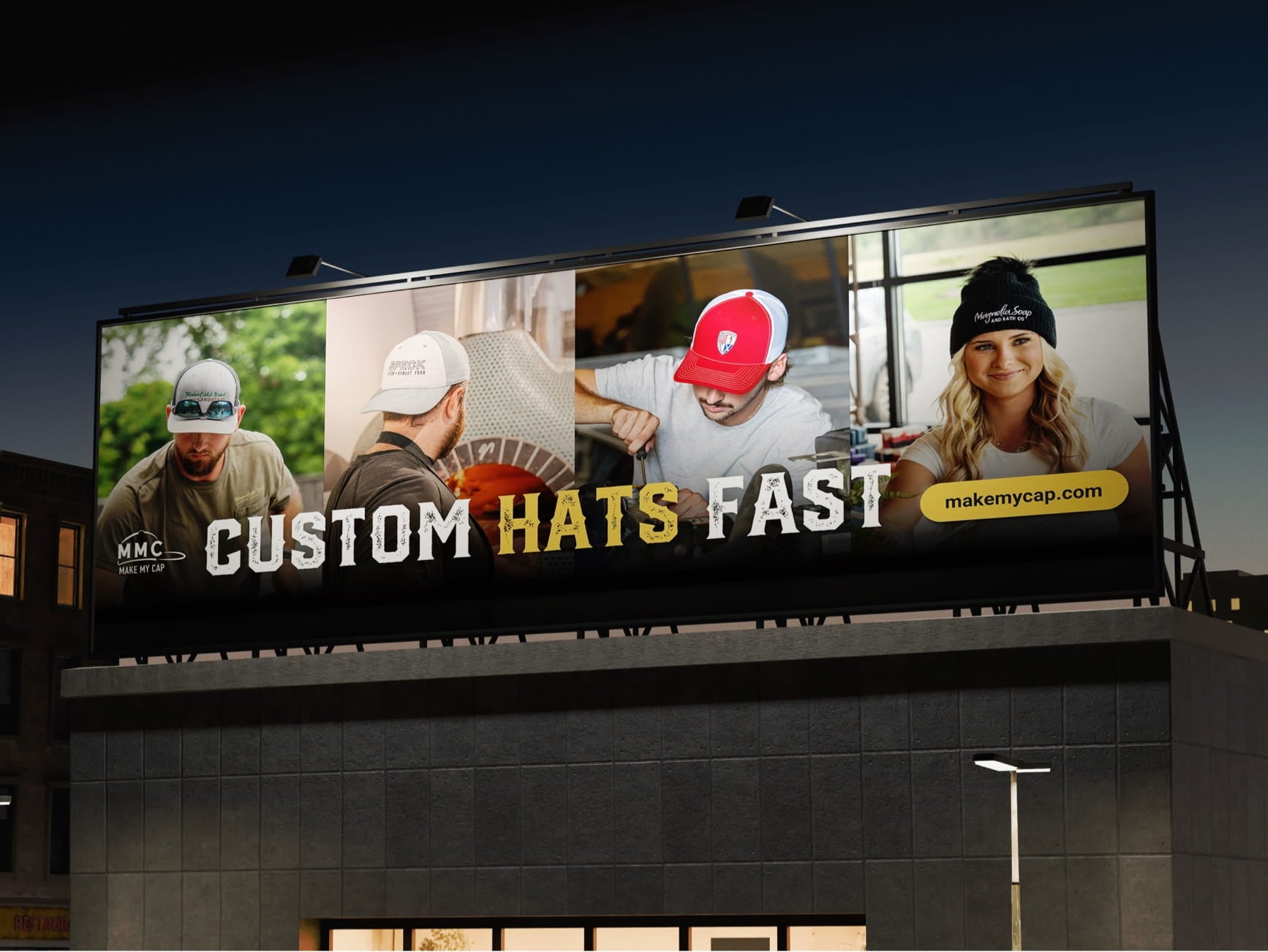 Nighttime billboard showing four people in custom hats, bold 'CUSTOM HATS FAST' text, MMC logo, and makemycap.com