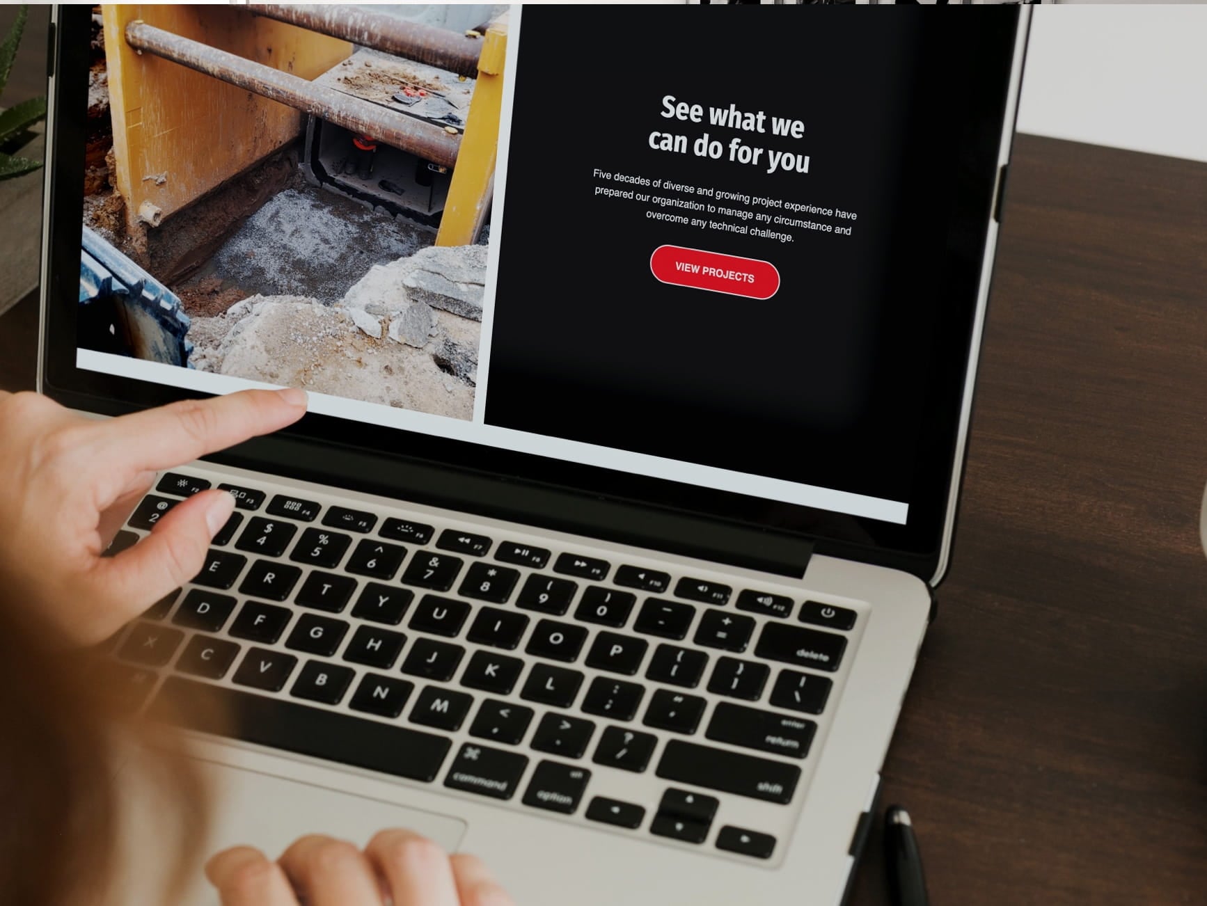 Hand points at laptop showing a construction photo, headline See what we can do for you, and a red View Projects button.