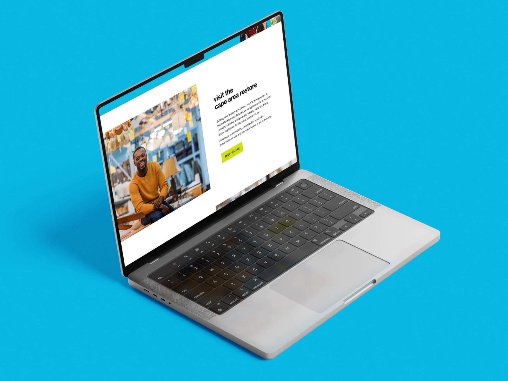 Laptop on blue background showing a webpage titled 'visit the cape area restore' with a photo of a smiling man in a yellow sw