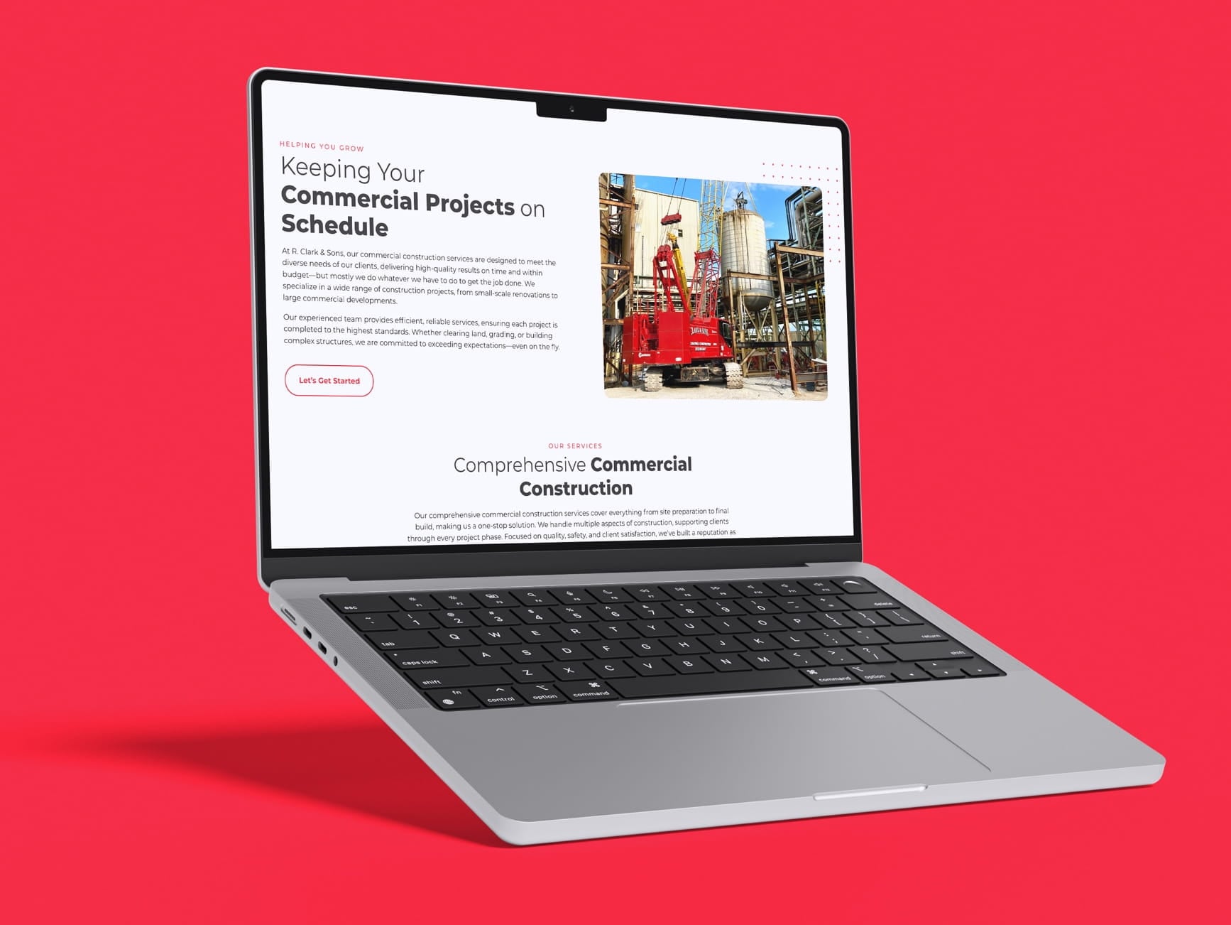 Silver laptop displaying a commercial construction website with red crane image and text about keeping projects on schedule.