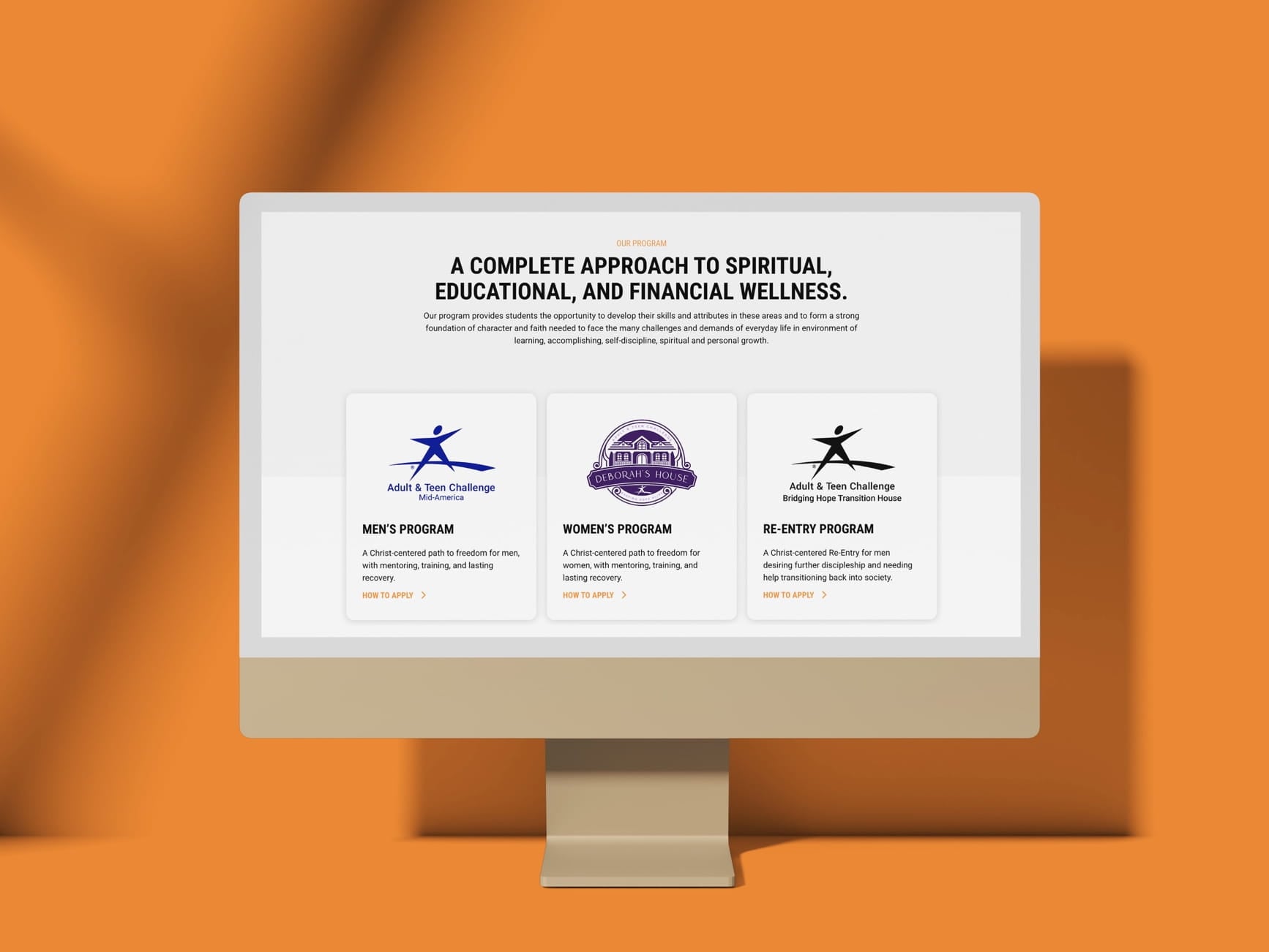 Monitor displays webpage with 'Our Program' heading and three cards: Men's, Women's, Re-Entry Christ-centered recovery.