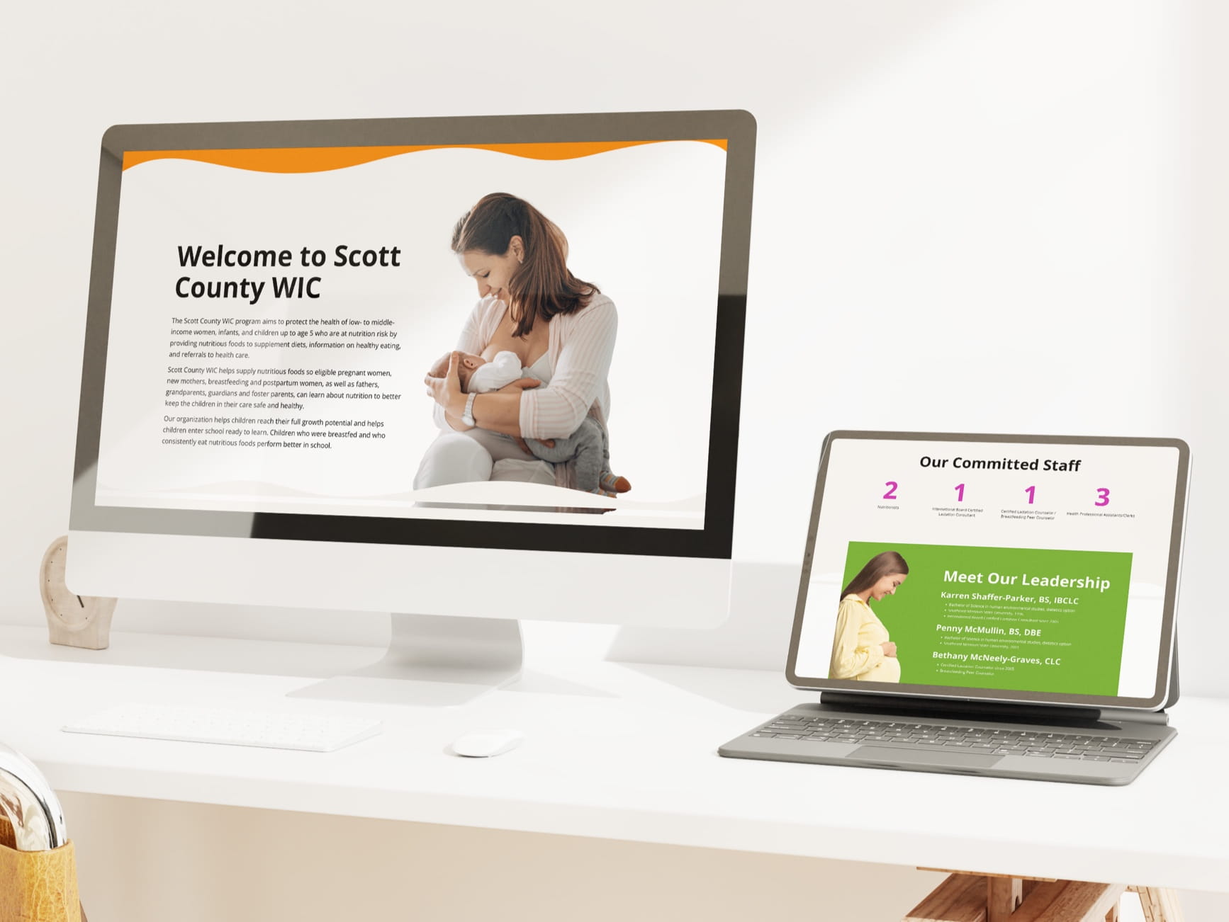 Desktop monitor and tablet on desk display Scott County WIC website with mother breastfeeding and staff leadership pages.